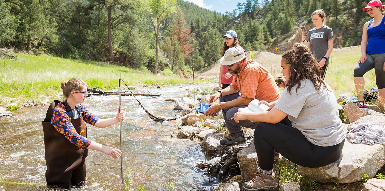 Students in the field collecting water from the Little Thompson River